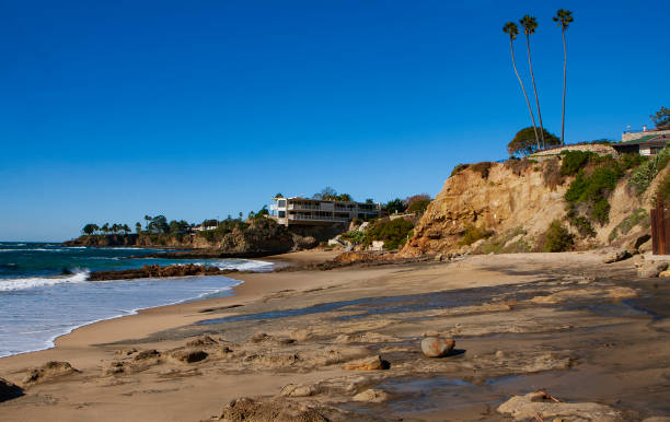 The view of the San Clemente waterfront at sunrise during a cloudless day featuring rocky beaches, tall palm trees and pricey beach-front real estate. stock photo