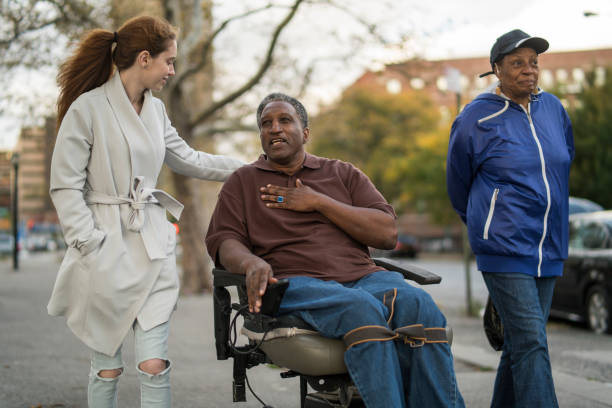 the white teenager girl talking with disabled wheel-chaired african american man and woman when they walking on the street together - wheelchair street imagens e fotografias de stock