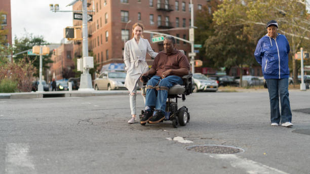 the white teenager girl talking with disabled wheel-chaired african american man and woman when they walking on the street together - wheelchair street happy imagens e fotografias de stock