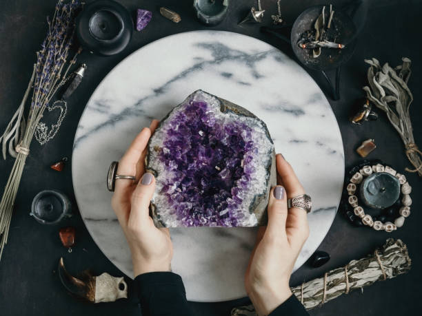 The witch is holding amethyst stone surrounded magic things. View from above. The witch is holding amethyst stone surrounded magic things. View from above. amethyst stock pictures, royalty-free photos & images