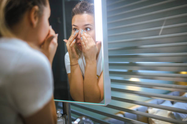 The woman applies the cream under the eyes before going to bed. stock photo