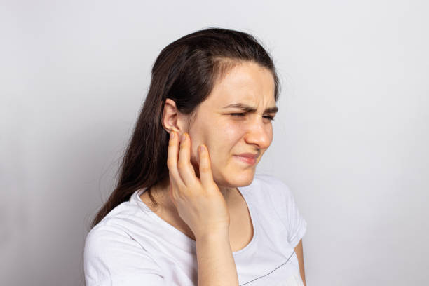 The woman has a sore ear - infection, inflammation from infection and otitis. Perforation ruptured the eardrum. Arthritis of the temporal lower jaw joint, osteoarthritis and pain in the jaw, mastoiditis Diseases and pain, inflammation in medicine and healthcare. human joint stock pictures, royalty-free photos & images
