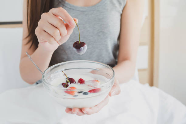 người phụ nữ cầm một bát sữa chua và trái cây dâu tây trên giường trắng vào buổi sáng. khái niệm chăm sóc sức khỏe phụ nữ. - yogurt hình ảnh sẵn có, bức ảnh & hình ảnh trả phí bản quyền một lần