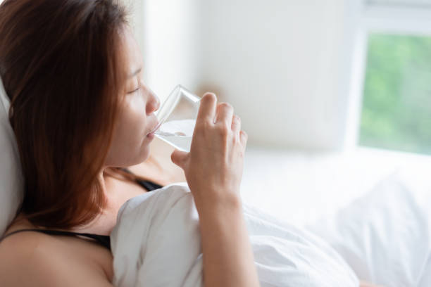 The woman with a fever and stayed at home. A woman with a fever drinks thirst. stock photo