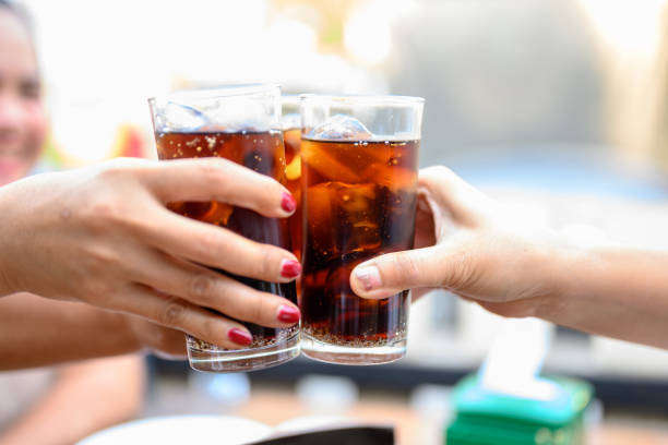 The woman's hand holds a glass of black soft drinks to drink. stock photo