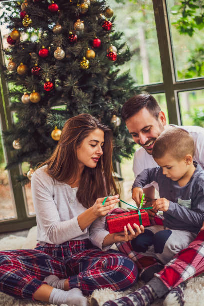 The wonder of Christmas morning A young boy opening a present with his parents on a Christmas morning. pinaceae stock pictures, royalty-free photos & images