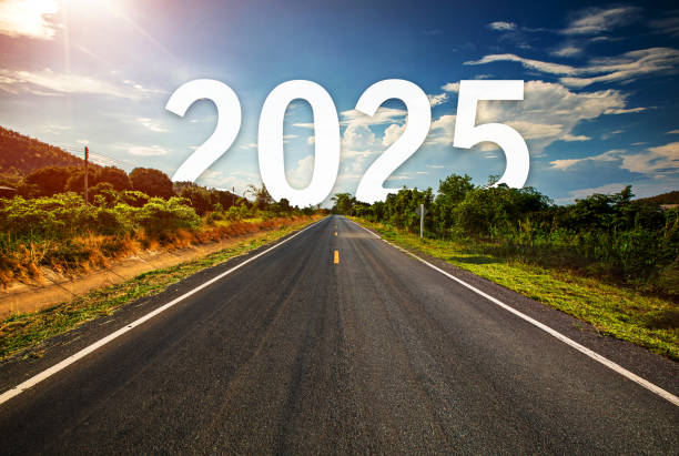 The word 2025 behind the tree of empty asphalt road at golden sunset and beautiful blue sky. stock photo