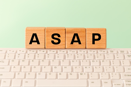 The word ASAP As soon as possible, Internet abbreviation used in communication, e.g. in business, The inscription on wooden blocks against the background of a computer keyboard