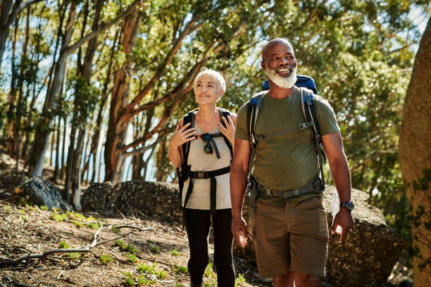 The world is just waiting to be explored Shot of a senior couple hiking together out in the mountains hiking stock pictures, royalty-free photos & images