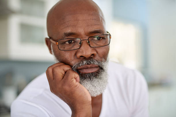 The years gone by leave much to think about Shot of a mature man looking thoughtful at home sad old black man stock pictures, royalty-free photos & images
