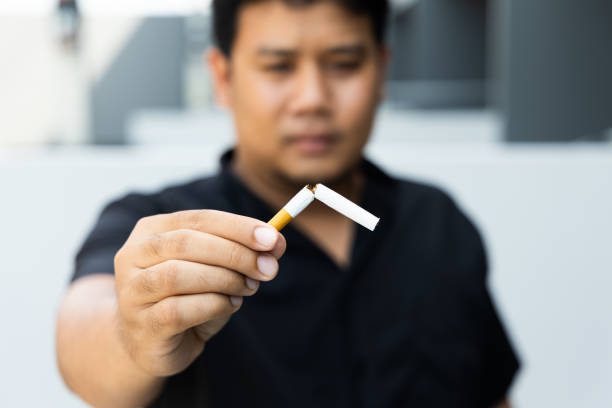 The young man used his hand to break a cigarette into two. He wants to quit smoking for good health. world tobacco day. stock photo