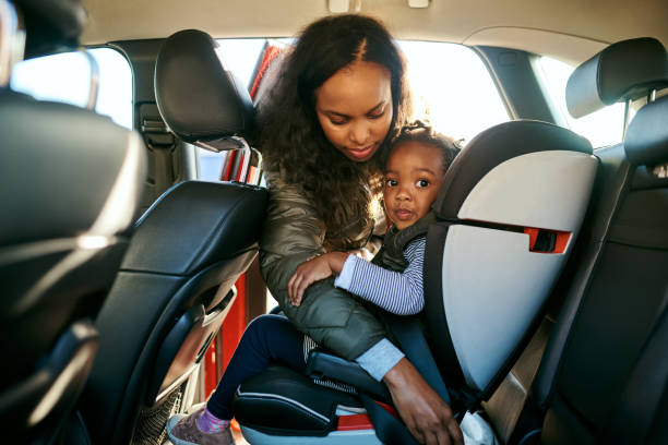 Their safety depends on you Shot of an adorable little girl being secured in her car seat by her mother fastening stock pictures, royalty-free photos & images