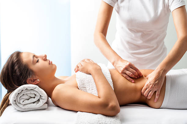 Therapist doing healing massage on female abdomen. stock photo