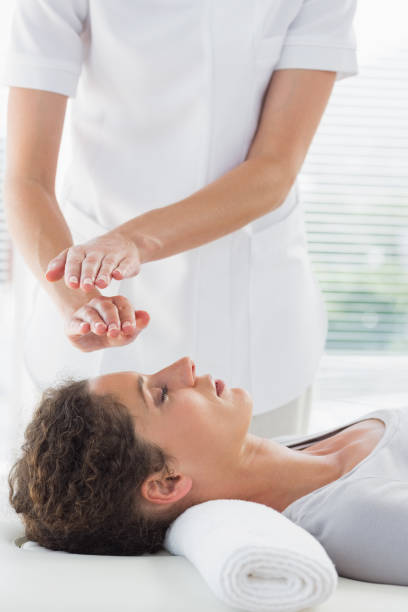 Therapist performing Reiki over woman Female therapist performing Reiki over woman at spa reiki stock pictures, royalty-free photos & images