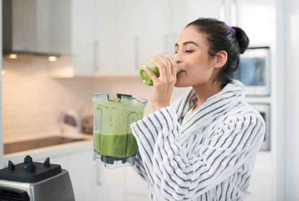 There's no better way to start your day! Cropped shot of a woman drinking a smoothie at home drinking smoothie stock pictures, royalty-free photos & images