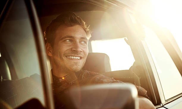 There's nothing quite like a roadtrip at sunset Shot of a handsome young man enjoying a roadtrip handsome people stock pictures, royalty-free photos & images