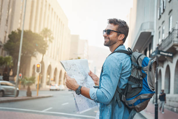 There's so much to see Shot of a young man looking at a map while touring a foreign city person looking at map stock pictures, royalty-free photos & images