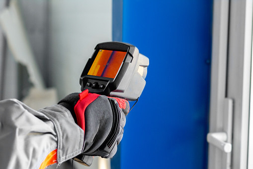 Thermal imaging. A thermal imager in the hands of an electrician conducting an inspection of the equipment