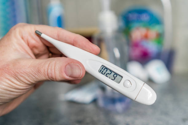 Thermometer reading a fever. Close-up of hand holding thermometer measuring a high fever fahrenheit stock pictures, royalty-free photos & images