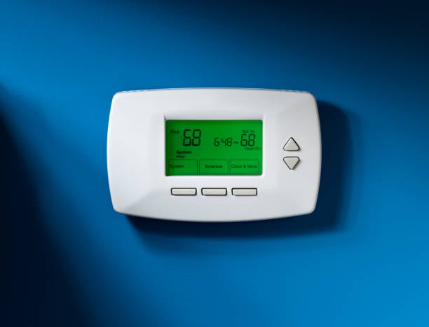Thermostat, Programmable, Isolated on blue Programmable thermostat set to 68 degrees.  Isolated on blue background with dramatic lighting. burwellphotography stock pictures, royalty-free photos & images
