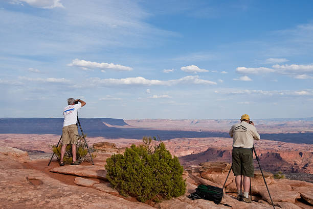 Two Photographers Lined Up on the Canyon Rim Canyonlands National Park, Utah, USA - May 17, 2012: These photographers are taking advantage of the evening light and clouds to shoot pictures from Grandview Overlook. jeff goulden canyonlands national park stock pictures, royalty-free photos & images