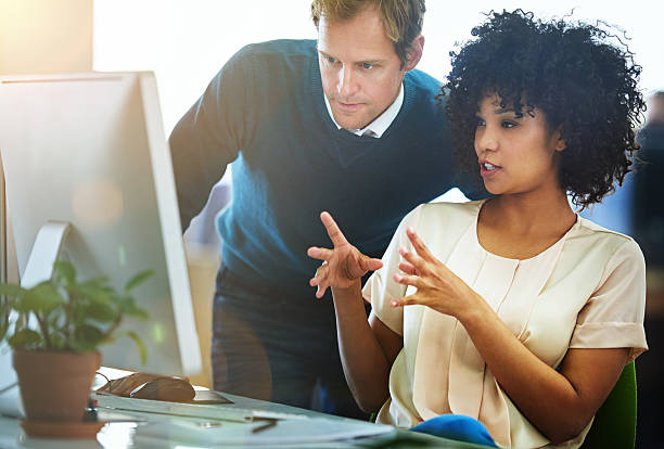 They know design Shot of two designers talking together while working on a computer in a modern office talented professionals stock pictures, royalty-free photos & images