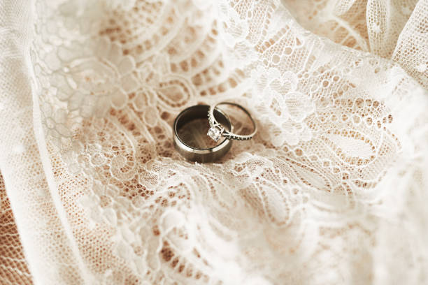 They symbolize our lifelong commitment to each other Still life shot of two beautiful wedding rings on top of a wedding dress wedding ring stock pictures, royalty-free photos & images