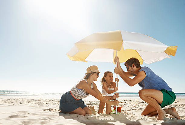 They're in it together Shot of a happy family putting their umbrella up at the beachhttp://195.154.178.81/DATA/i_collage/pu/shoots/784349.jpg protection stock pictures, royalty-free photos & images