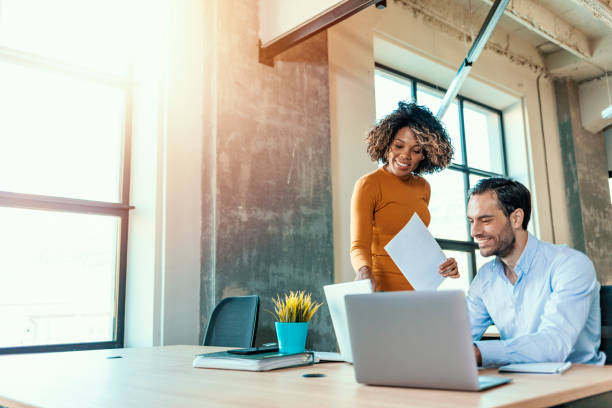 They're staying ahead of the game with their ideas We already have great results! Young beautiful woman working, discussing something with her coworker while standing at office. software stock pictures, royalty-free photos & images