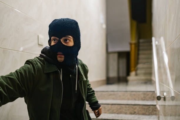 thief with mask quickly leaving a house thief with face mask quickly leaving a building ski mask criminal stock pictures, royalty-free photos & images