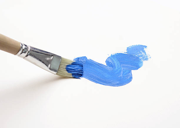 Thin brush leaving a blue watercolor streak on white surface stock photo