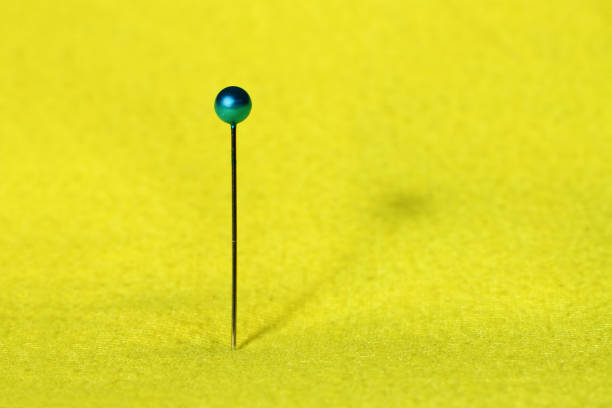Thin needle on the yellow fabric. stock photo
