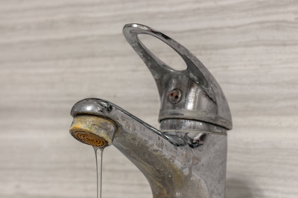 A thin stream of hard water flows from an old tap aerator. Old Bathroom Sink Faucet contaminated with calcium and grime. A thin stream of hard water flows from an old tap aerator. Old Bathroom Sink Faucet contaminated with calcium and grime. toughness stock pictures, royalty-free photos & images