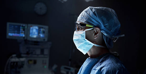 Thinking about the proper decision Shot of a surgeon in an operating room surgeon stock pictures, royalty-free photos & images