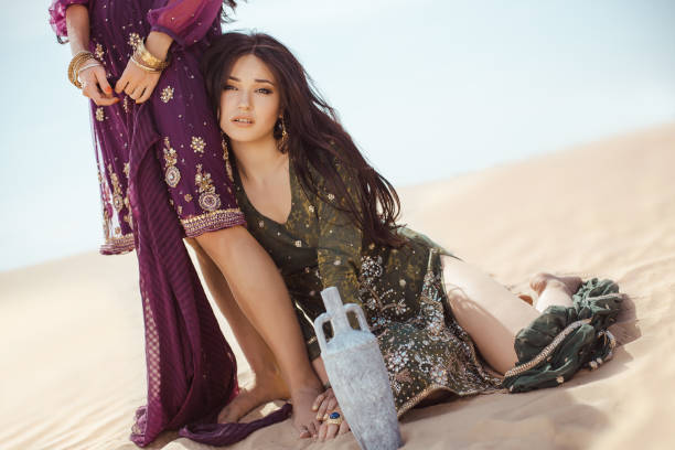 Thirsty women traveling in desert. Lost in desert durind sandshtorm Women traveling in desert. Dehydration, overheating, thirst and heat stroke concept image with two sisters outdoors in the nature. Arabian girls lost in dunes during journey. hot arabic girl stock pictures, royalty-free photos & images