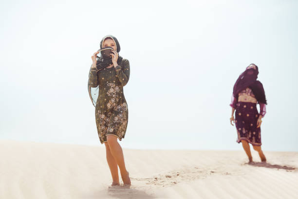Thirsty women walking in a desert. Lost during the travel Desert women thirsty dehydrated tired walking outdoors. Dehydration, overheating, thirst and heat stroke concept image with two sisters in desert nature. Beautiful mixed race asian caucasianl arabian girls lost in desert during journey. hot arabic girl stock pictures, royalty-free photos & images