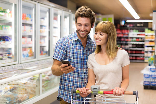 Thirty-year-old couple using mobile phone in supermarket stock photo