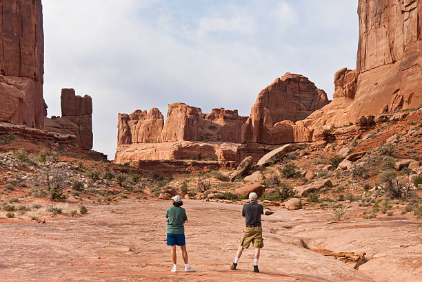 Photographing in Park Avenue Arches National Park, Utah, USA - May 16, 2012: This couple stops to take a picture while hiking on the Park Avenue Trail. jeff goulden arches national park stock pictures, royalty-free photos & images