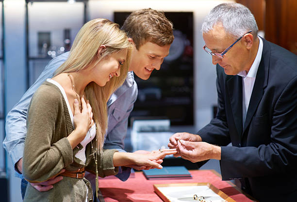 This decision will last a lifetime Happy young couple trying on engagement rings in a jewelery store store clerk selling jewelry stock pictures, royalty-free photos & images