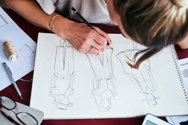 This is my newest collection Cropped shot of a fashion designer working on new sketches at her desk fashion design sketches stock pictures, royalty-free photos & images
