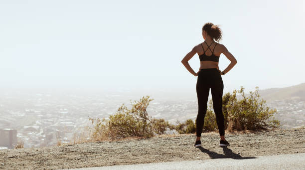This view inspires me to go even further Rearview shot of a sporty young woman admiring the view while exercising outdoors hand on hip stock pictures, royalty-free photos & images