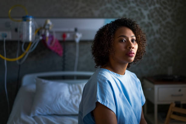 Thoughtful female patient sitting at hospital stock photo