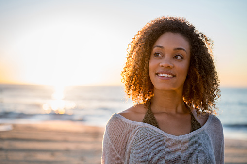 Portrait of a thoughtful black woman at the beach looking up and smiling