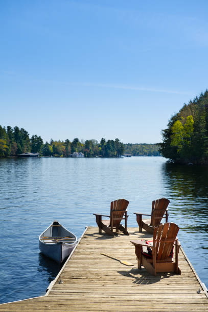 Three Adirondack chairs on a wooden dock stock photo
