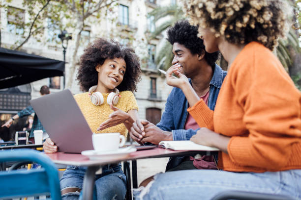 Three Afro friends in Barcelona sitting at the cafe  and using laptop stock photo