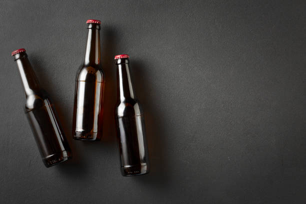 three beer bottles on black concrete background with copy space. - empty beer bottle imagens e fotografias de stock