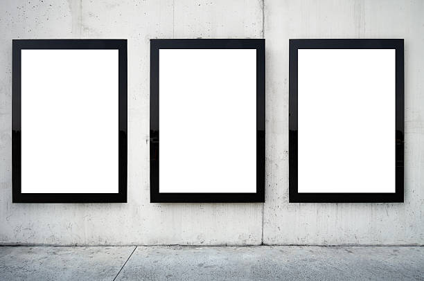 Three blank billboards on wall. Blank billboards on wall. Wall is made of concrete and gray coloured. There are three billboards standing side by side and oriented vertically. Edges of billboards are black. Billboards are empty so you can write or add something on them. - Clipping path of billboards included. poster stock pictures, royalty-free photos & images