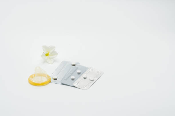 trois sous blister pack de pilules contraceptives d’urgence avec préservatif et fleurs sur fond blanc - pilule du lendemain photos et images de collection