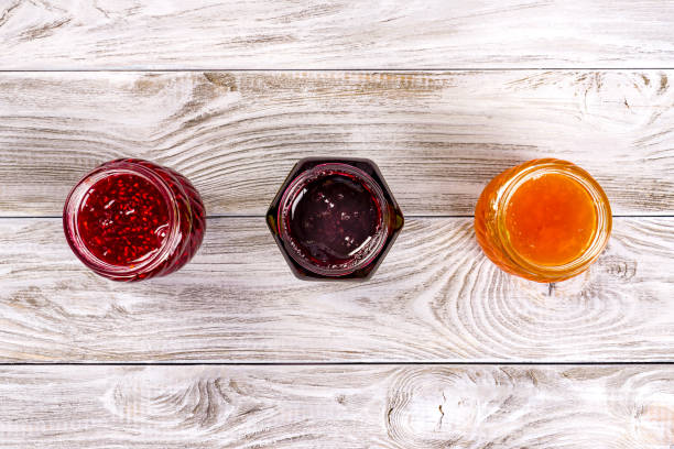 Three bowls with different jams on wooden table. Top view stock photo