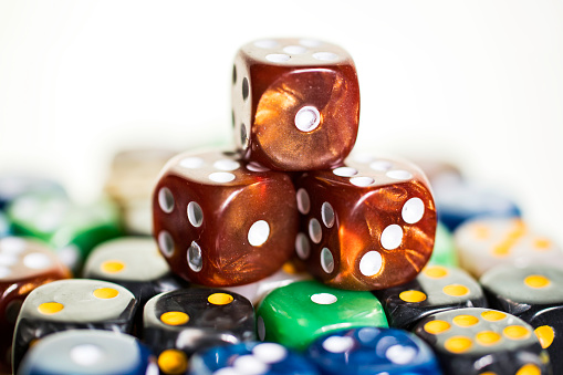 Three brown copper dice sitting on colored dice against a white background in a casino